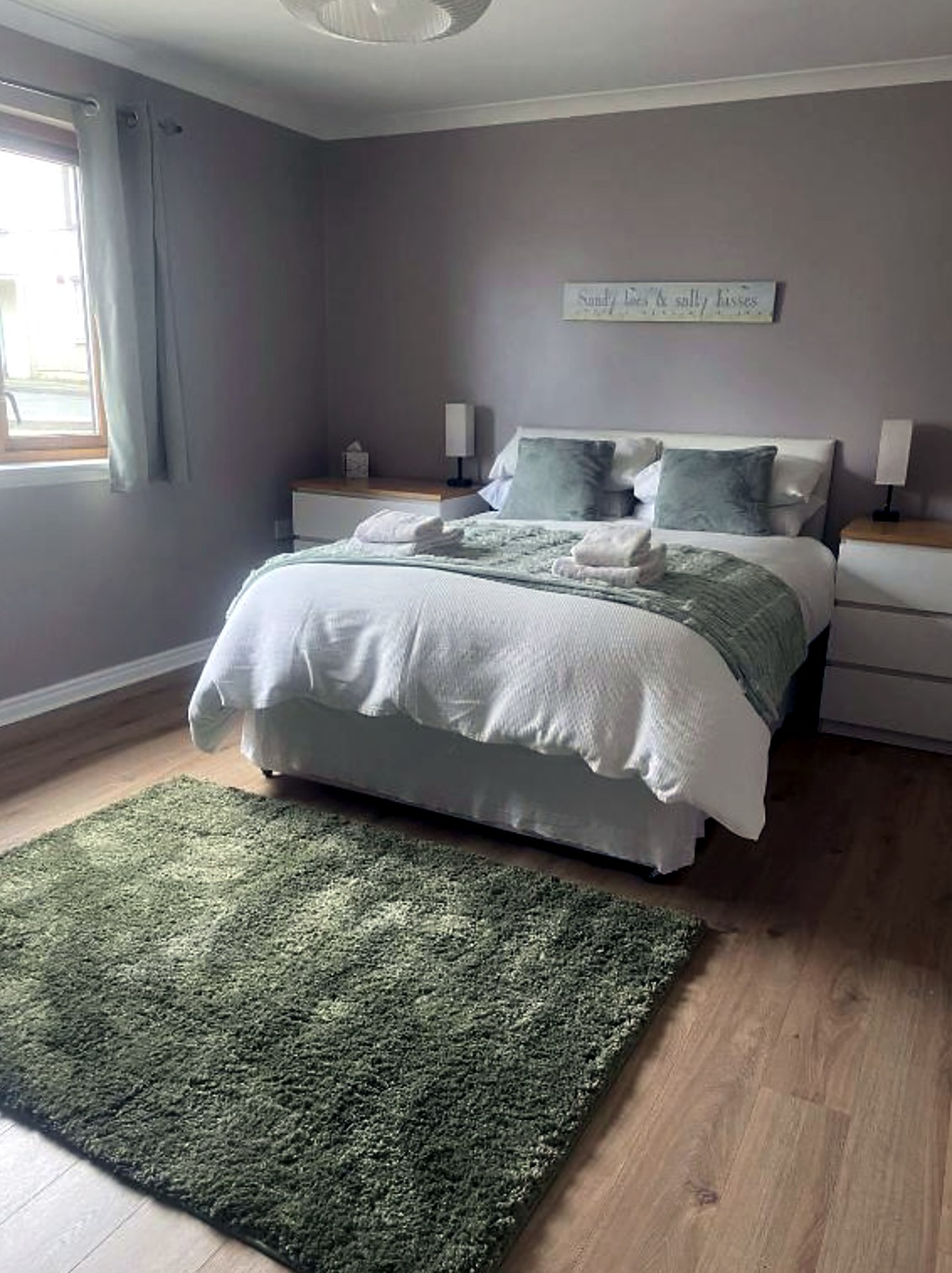 Double bedroom at Fraoch with green throw, rug and white bedside drawers