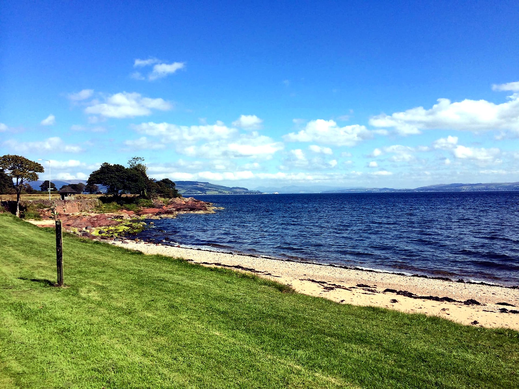 Sandy shore, red sandstone rocks and the Firth of Clyde at Kerrycroy on the Isle of Bute