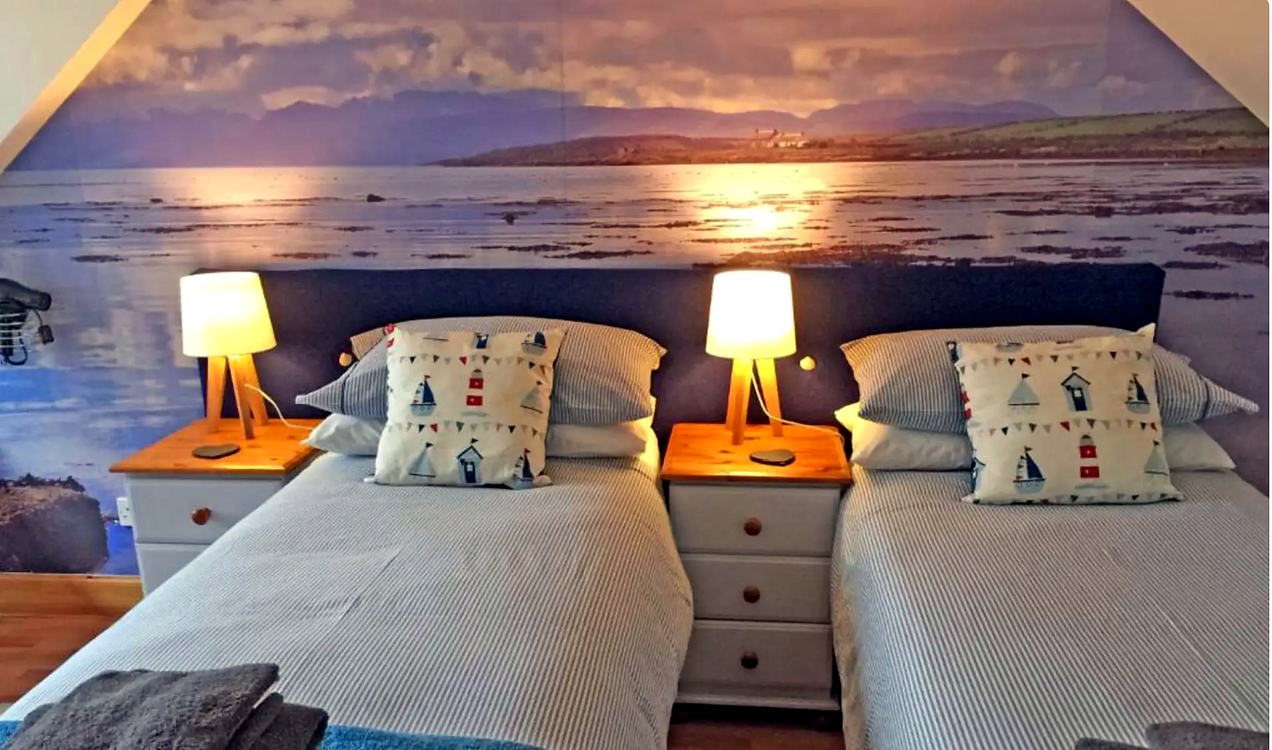 Twin bedroom at Old Fisherman's Cottage with nautical cushions and bedside lamps