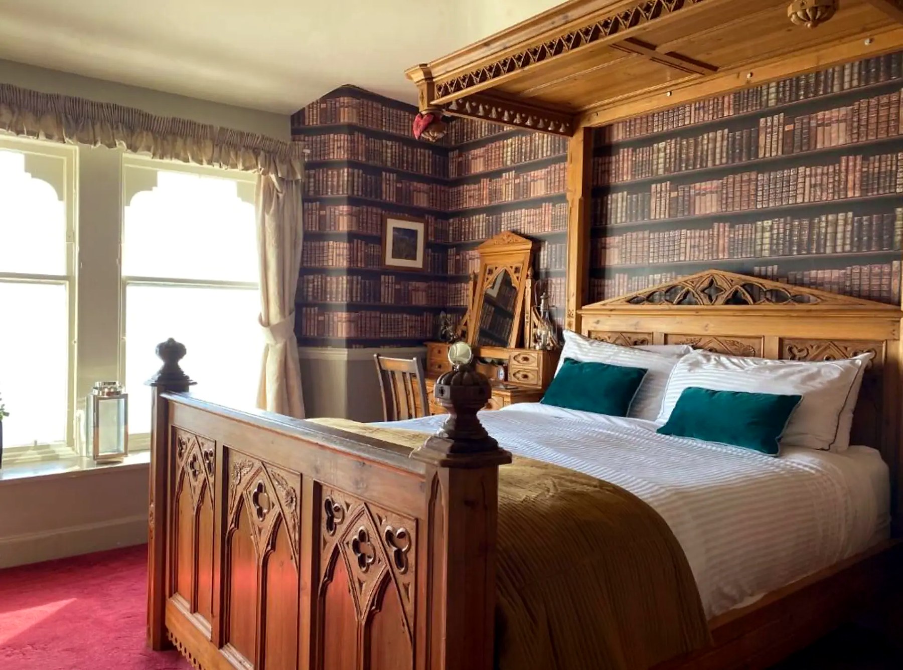 Gothic carved bed and library wallpaper in a sunlit bedroom at St Blanes House