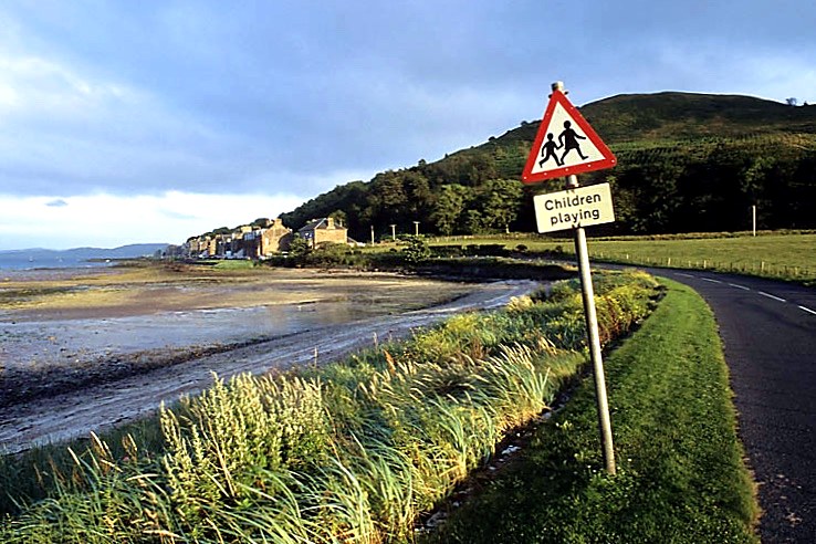 Shore road and grasses looking along the sands to the village at Kilchattan Bay, Isle of Bute