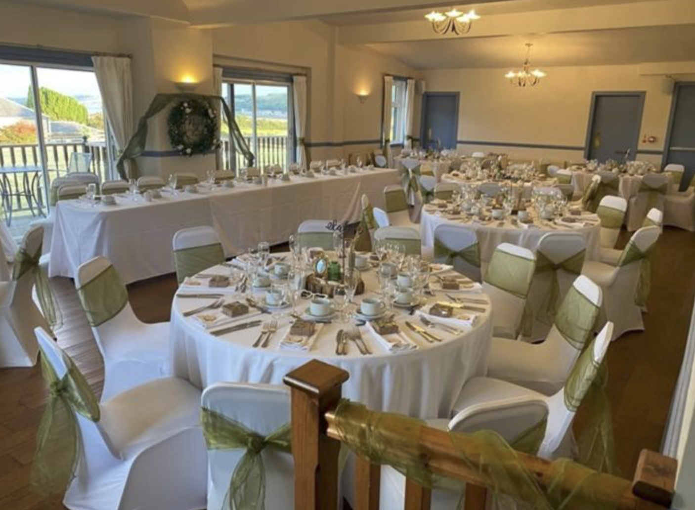 The function room at the Kingarth Hotel set for a wedding, with round tables, chair covers and a balcony view