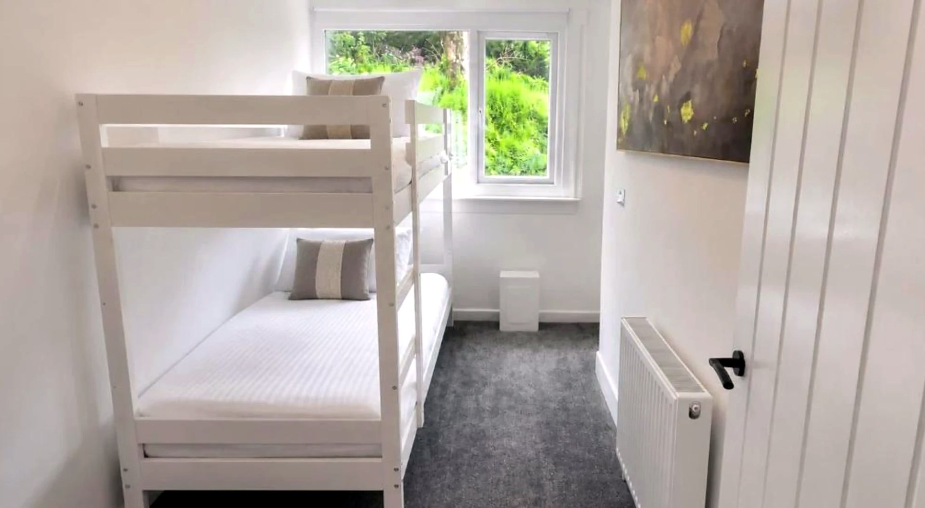 Bunk room with white bunk beds and a garden window at Bayview at the Port
