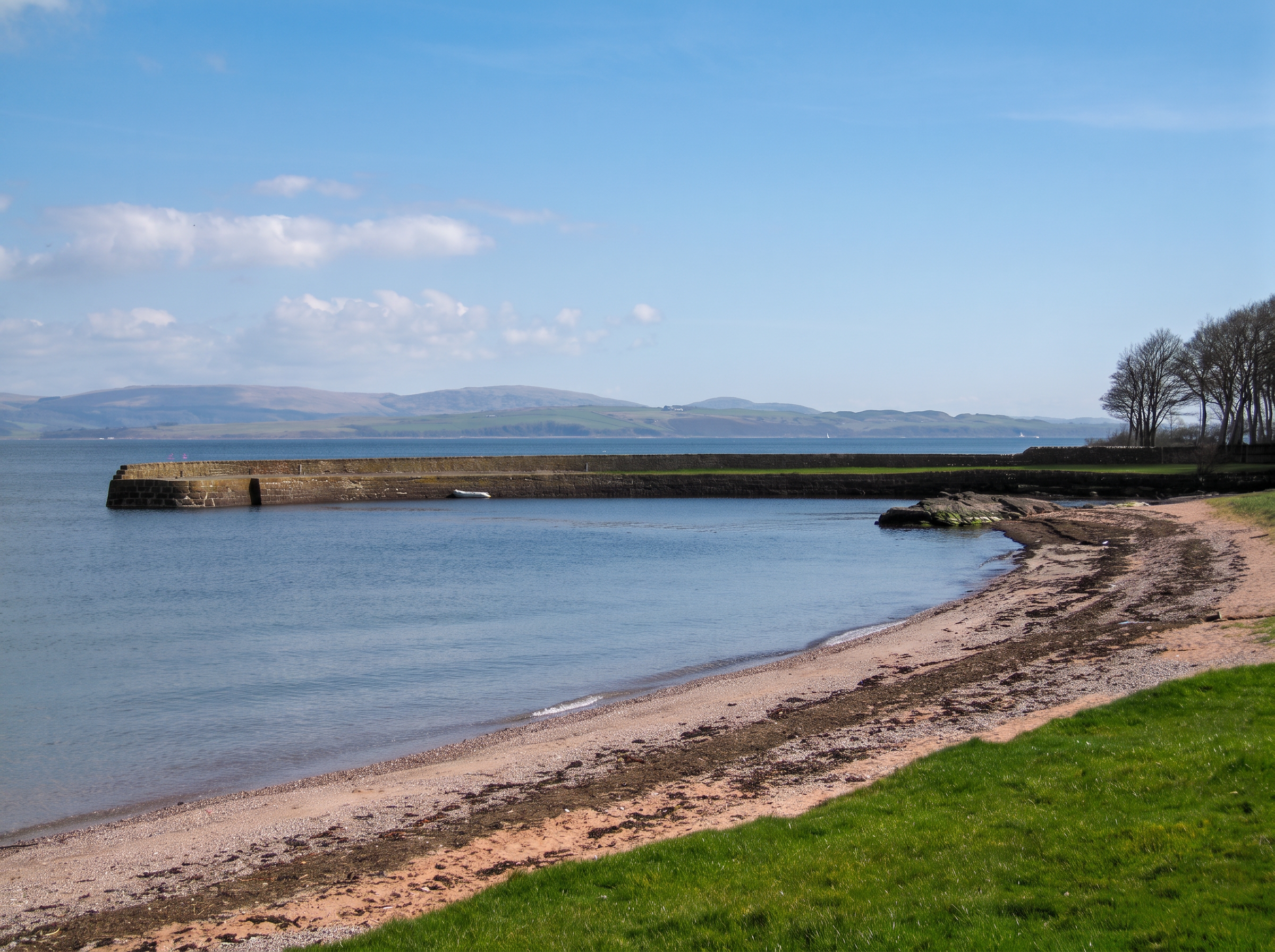 Old stone pier and shingle beach on Bute, looking across to the mainland hills