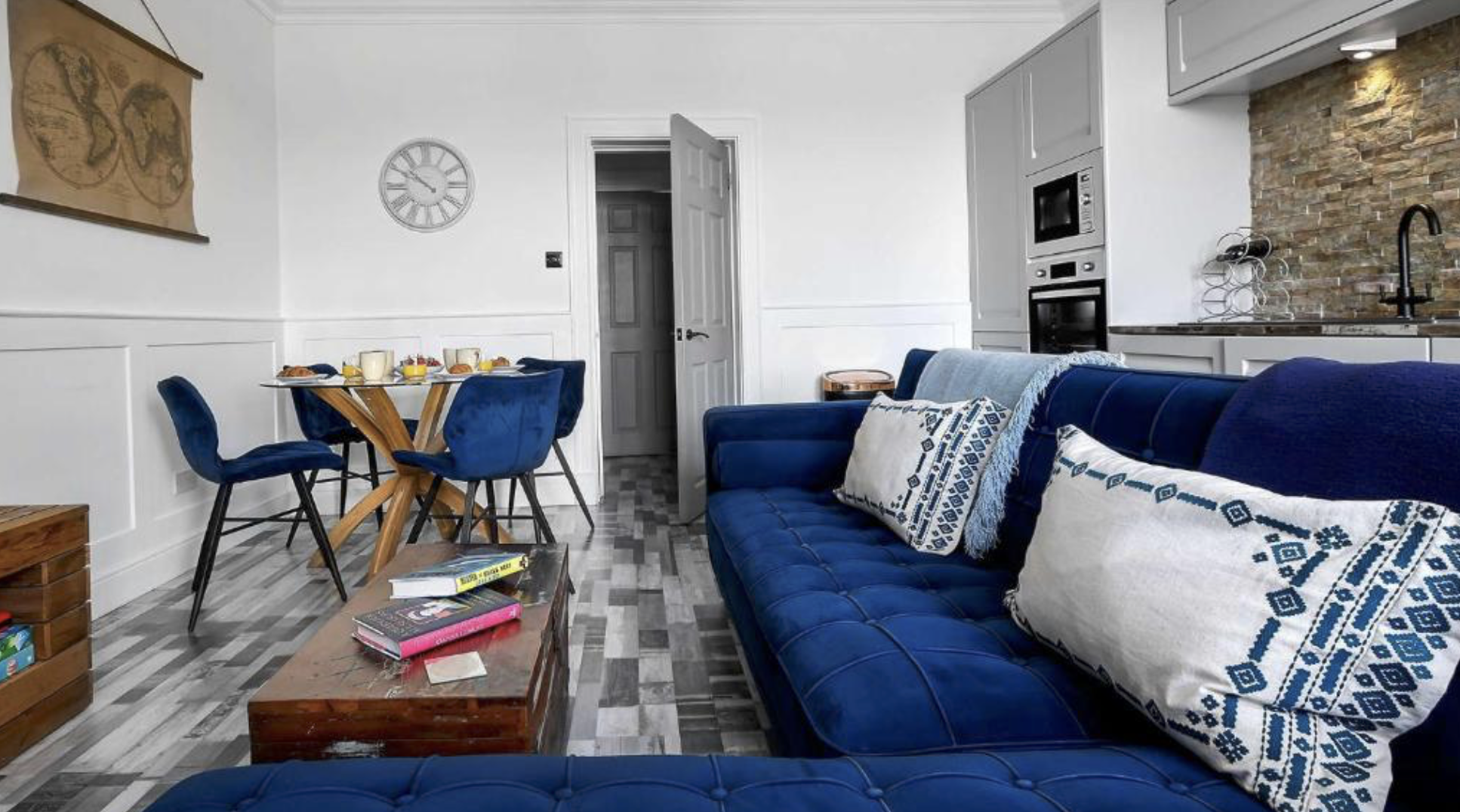 Blue velvet sofas, dining table and modern kitchen in the open-plan living space at Melbourne Place