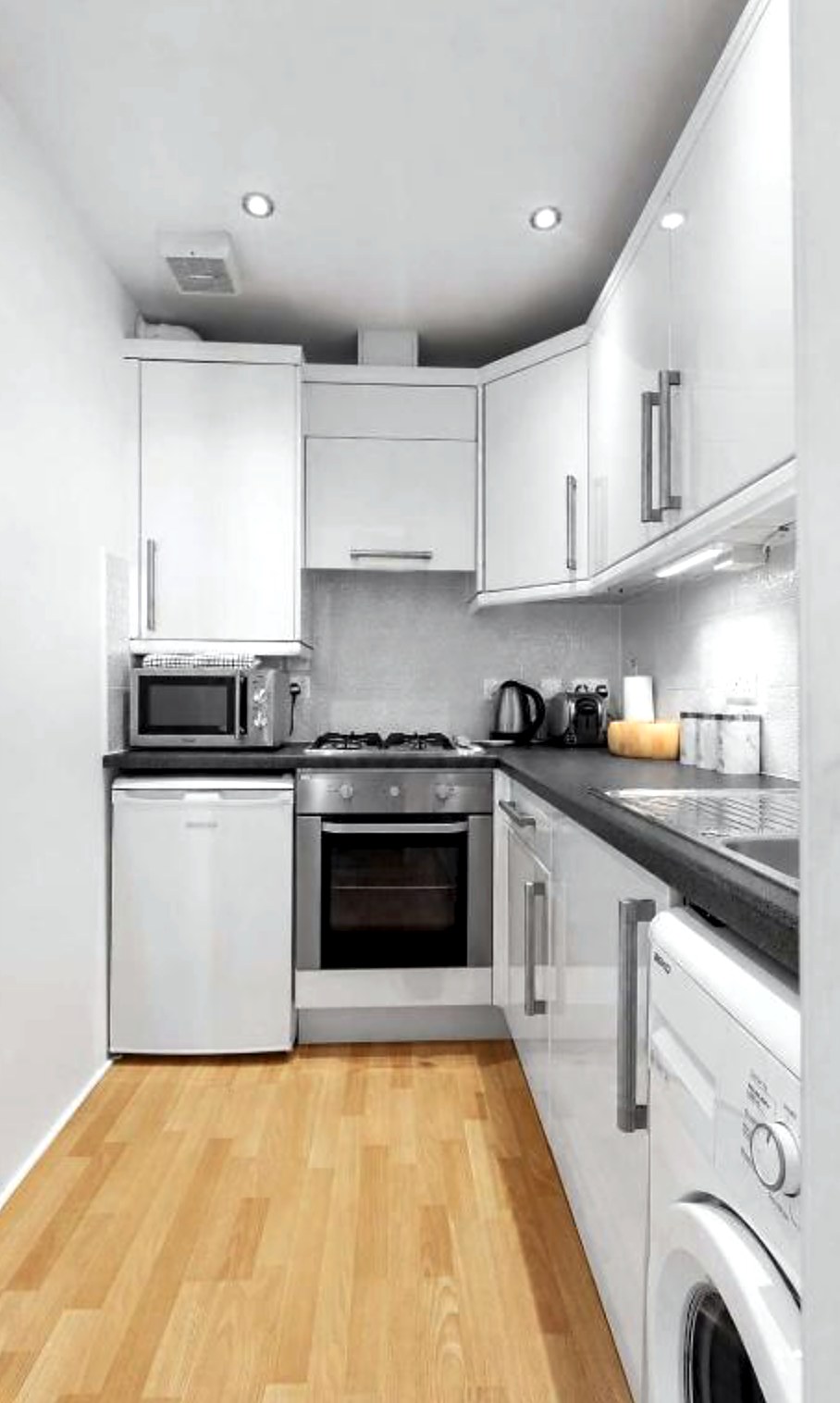 Compact white galley kitchen at Above the Bay with gas hob, oven and washing machine