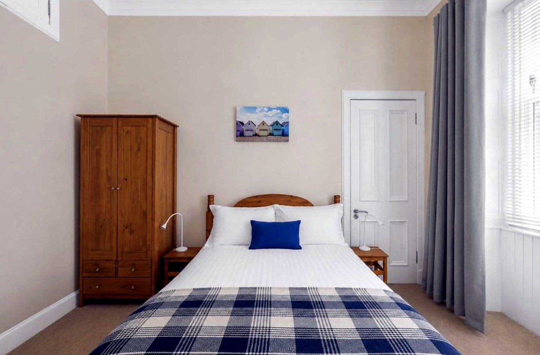 Double bedroom at Above the Bay with pine wardrobe, tartan throw and tall sash window