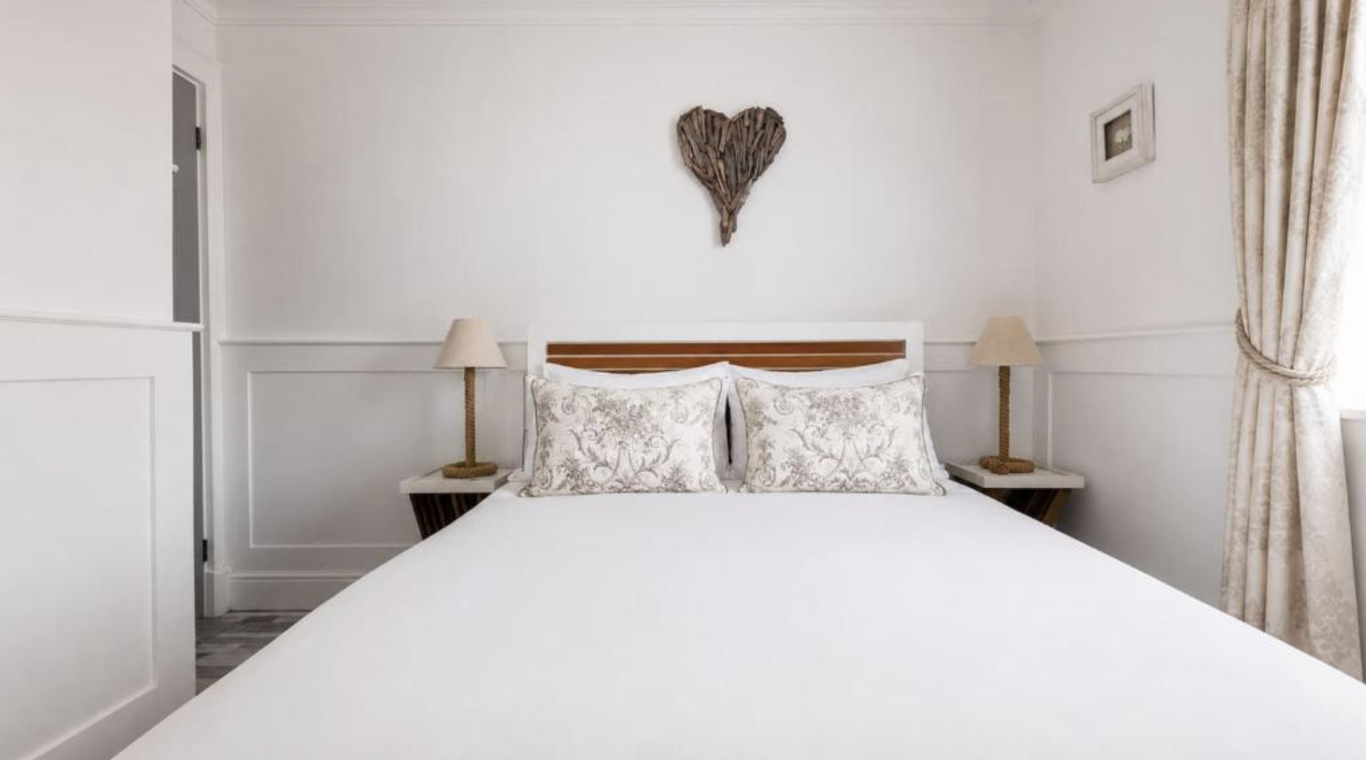 A second double bedroom at Melbourne Place with soft white linen and a garden view