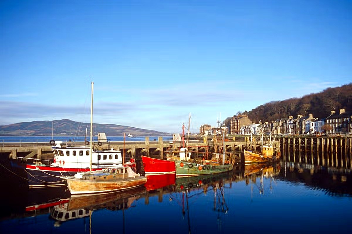Fishing boats reflected in the still water of Rothesay harbour on a clear winter morning