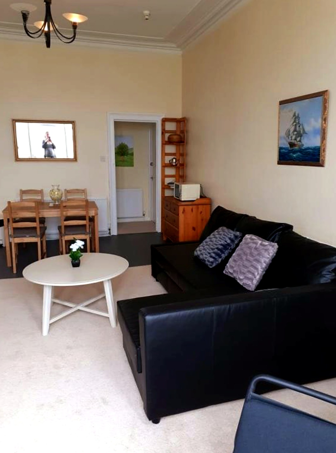 Open living and dining space in a Commodore apartment with sofa, dining table and sea paintings