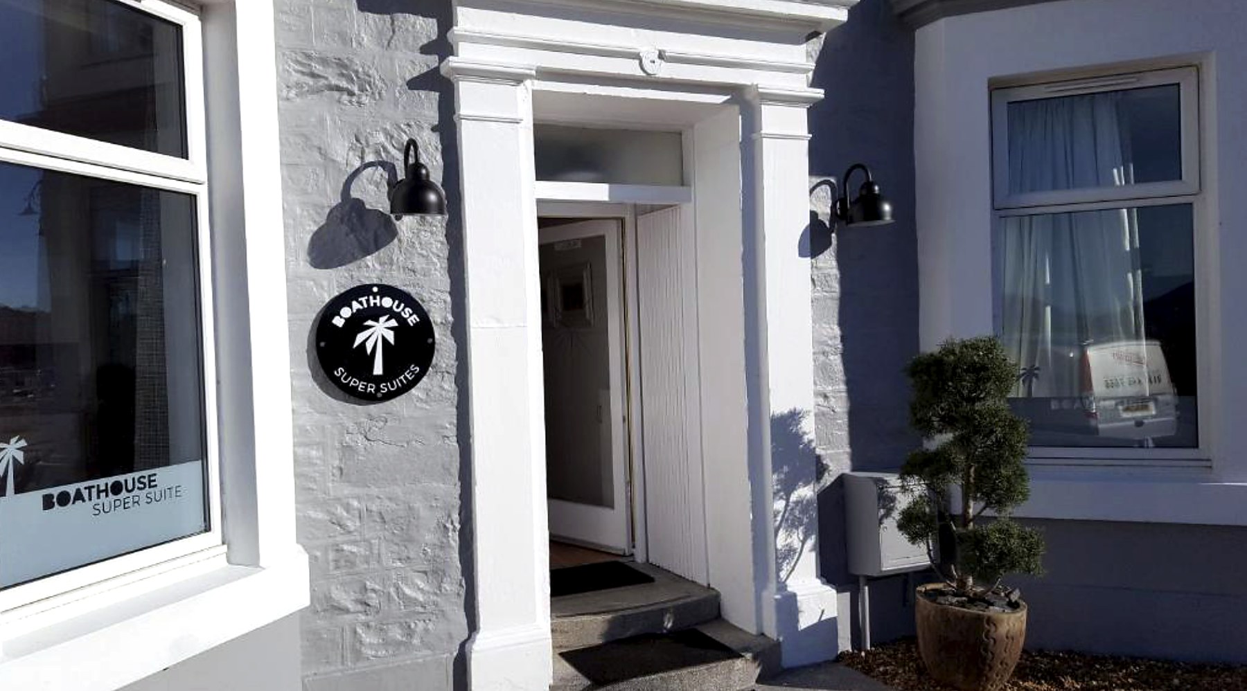 White pillared entrance porch with lanterns on a grey stone seafront building