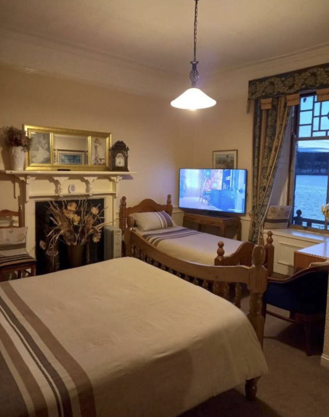 A twin room at Battery Lodge with a fireplace, pine beds and a window over Rothesay Bay