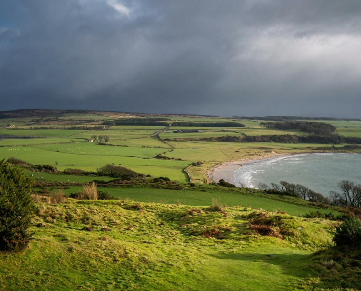 Green farmland running down to a sandy bay on the south-west coast of Bute