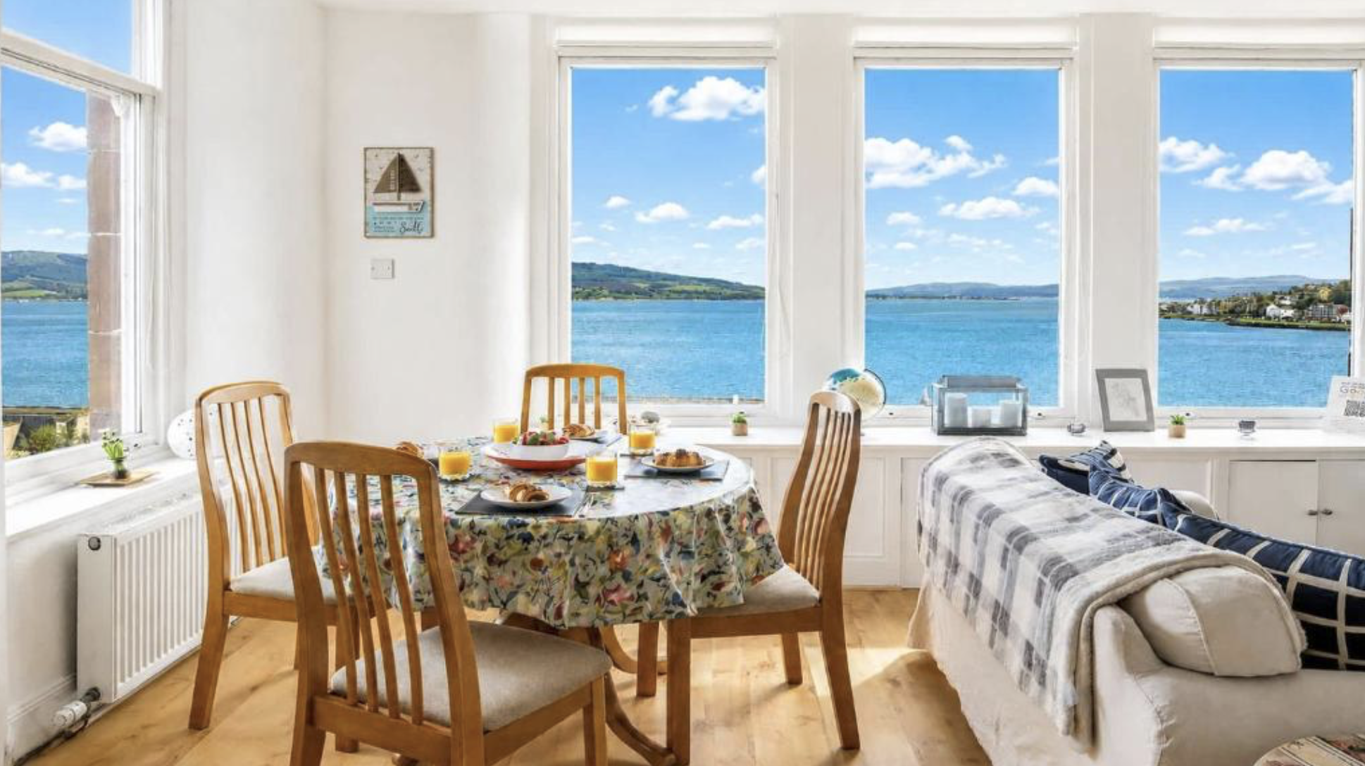 A dining table in a bay window at The Hidden Asset, with the Firth of Clyde beyond