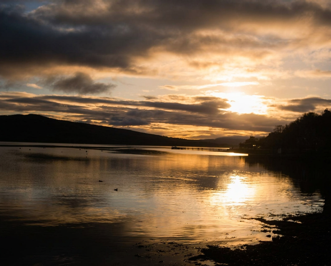 Sunset over calm water and a wooden jetty on the Isle of Bute