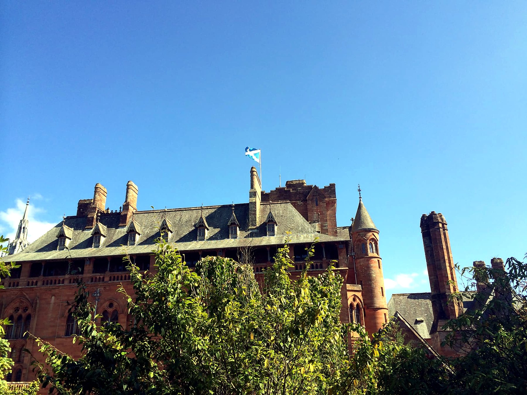 The Saltire flying from the tower of Mount Stuart House on the Isle of Bute against a clear blue sky
