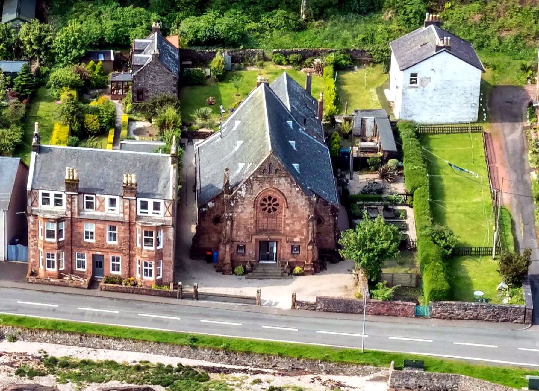Aerial view of the converted church and neighbouring houses beside the shore road on Bute