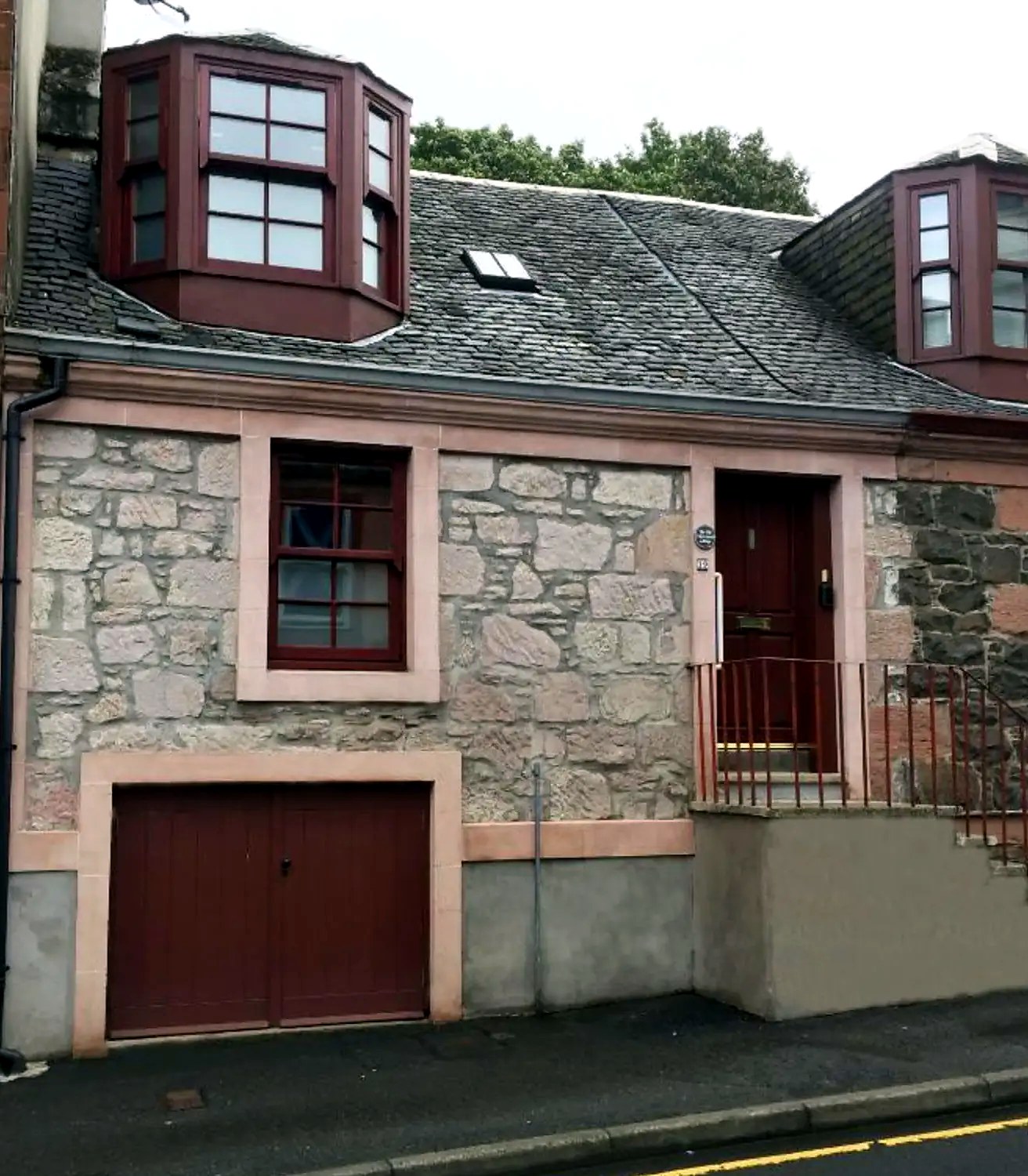 Stone exterior of Old Fisherman's Cottage with red bay windows