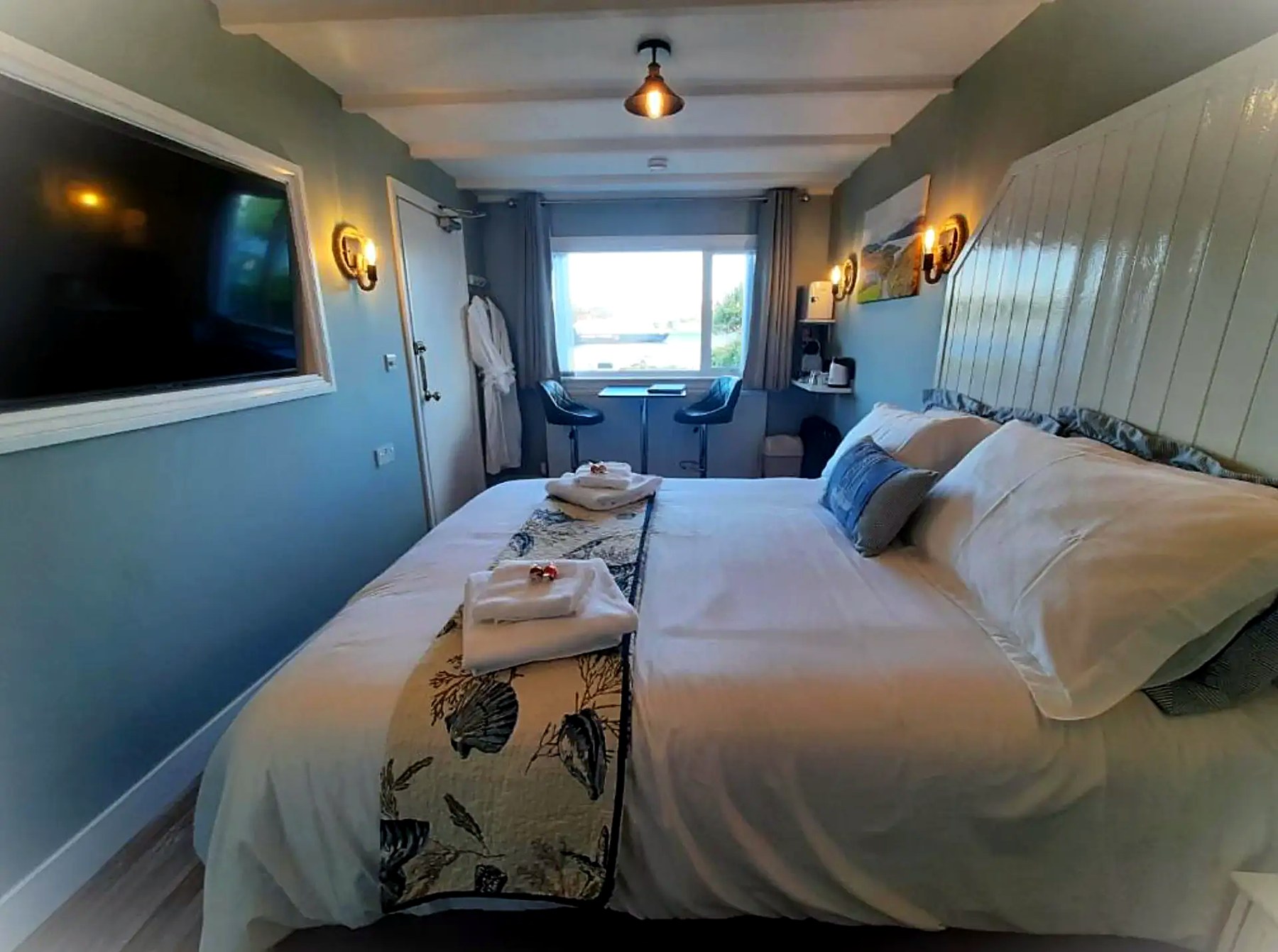 Beamed coastal-themed bedroom at Highlander House with panelled headboard and shell-print throw