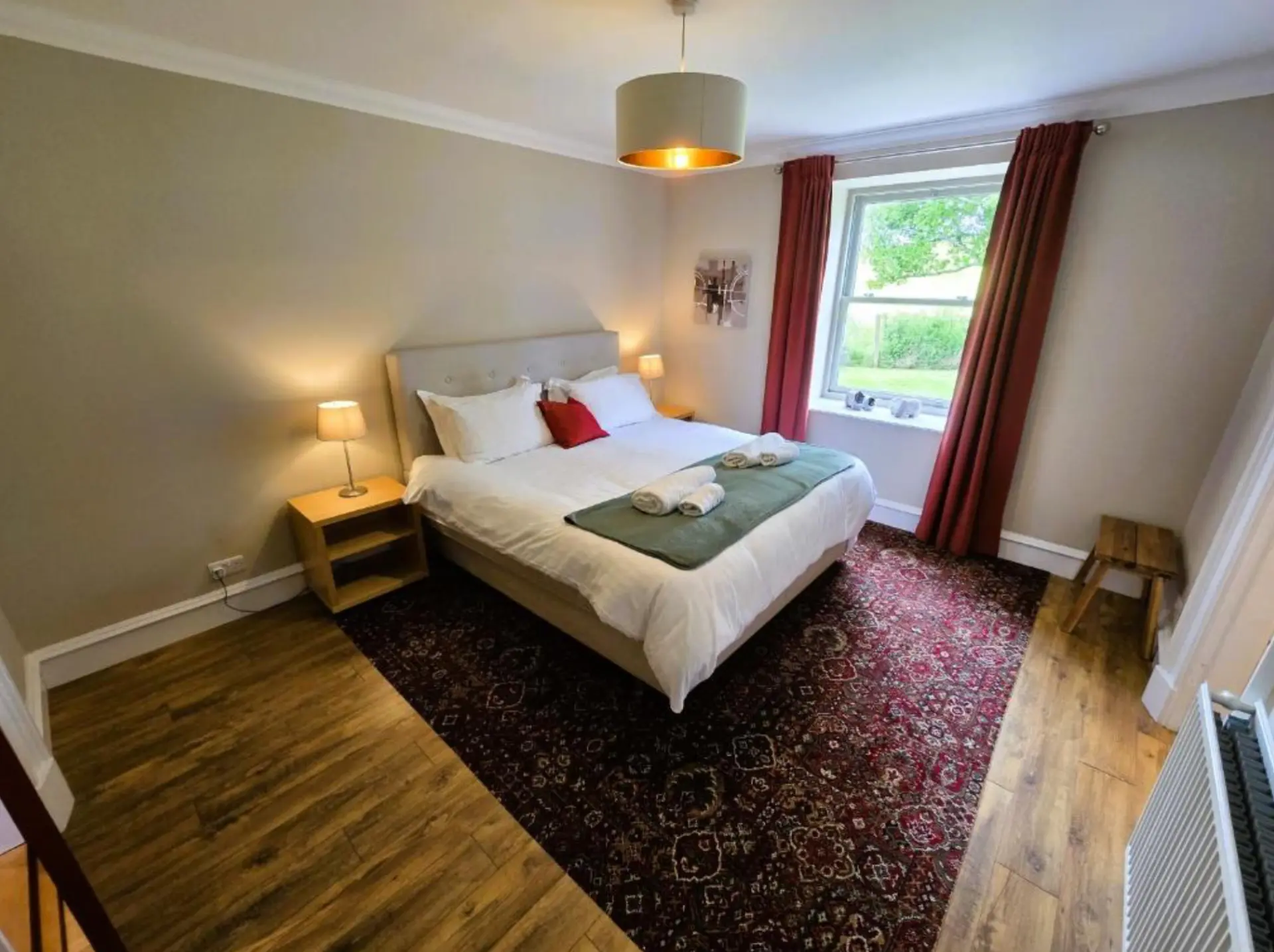 A double bedroom at Balmory Stables with a window over the garden and towels on the bed