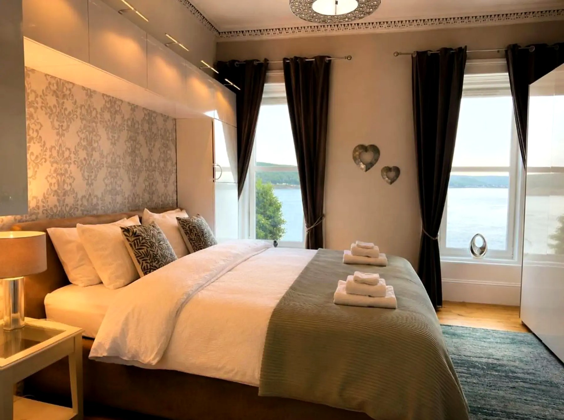Bedroom at Harbour View with a large bed and two windows looking over Rothesay Bay