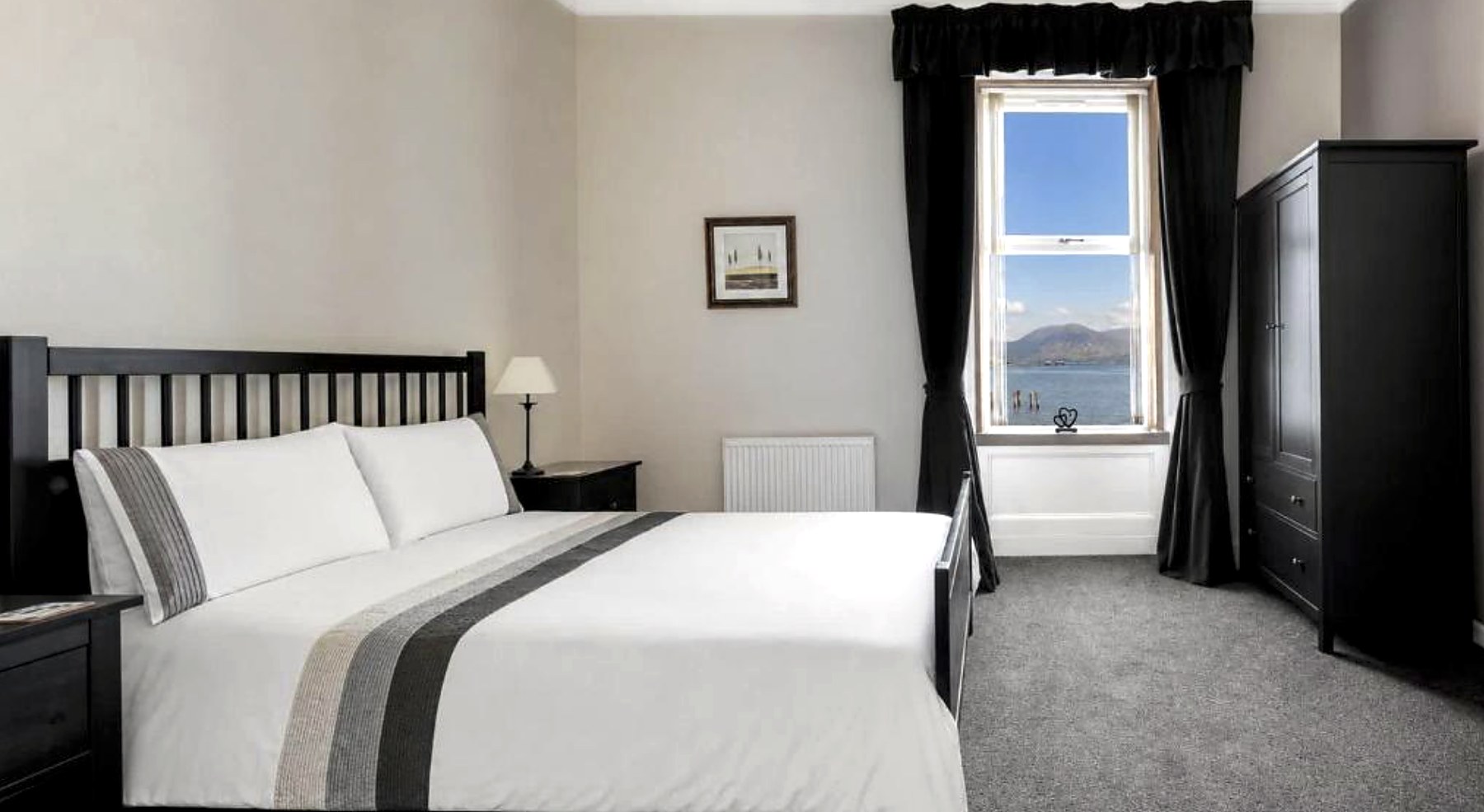 Bedroom at Ardyne House with a black wooden bed and sea view through the sash window