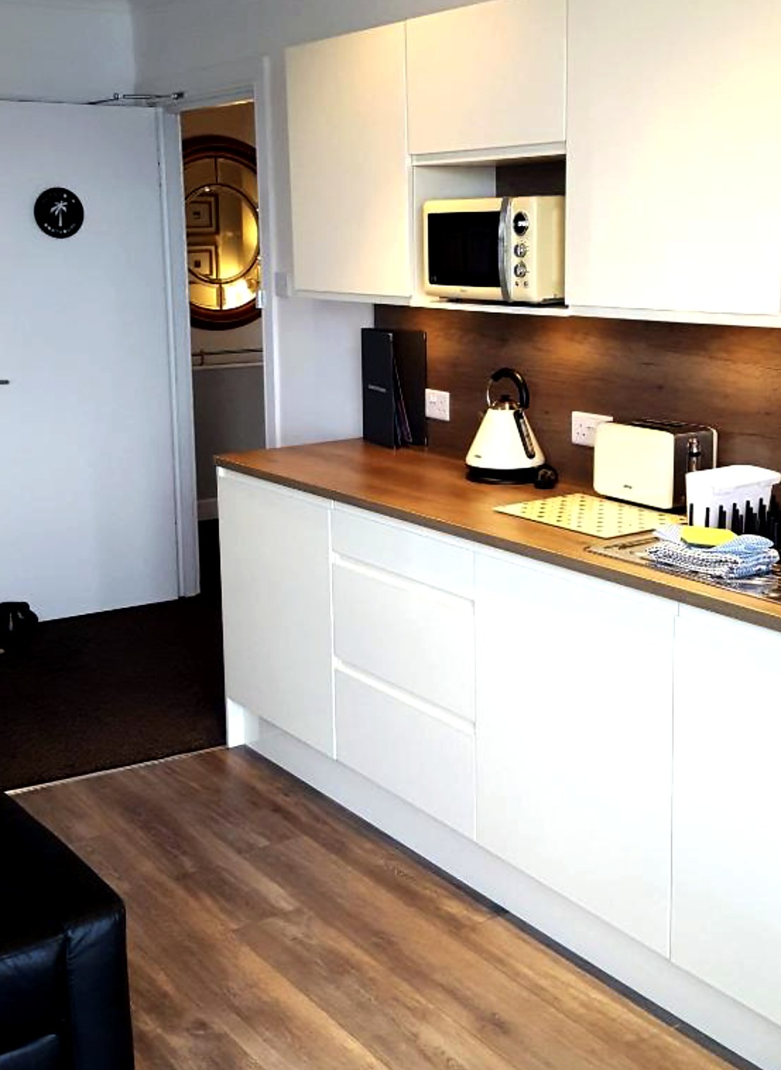 White fitted kitchen with wooden worktop, kettle and toaster