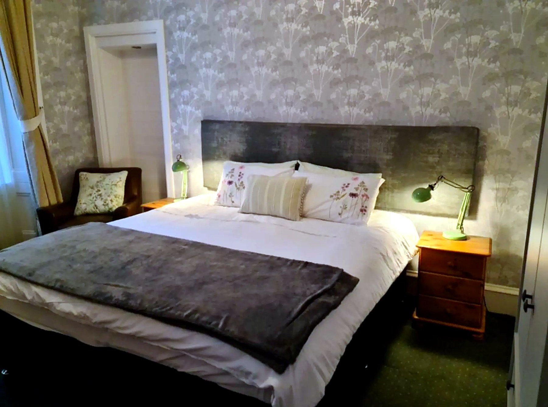 King-size bedroom at St Ebba's with patterned wallpaper and reading lamps