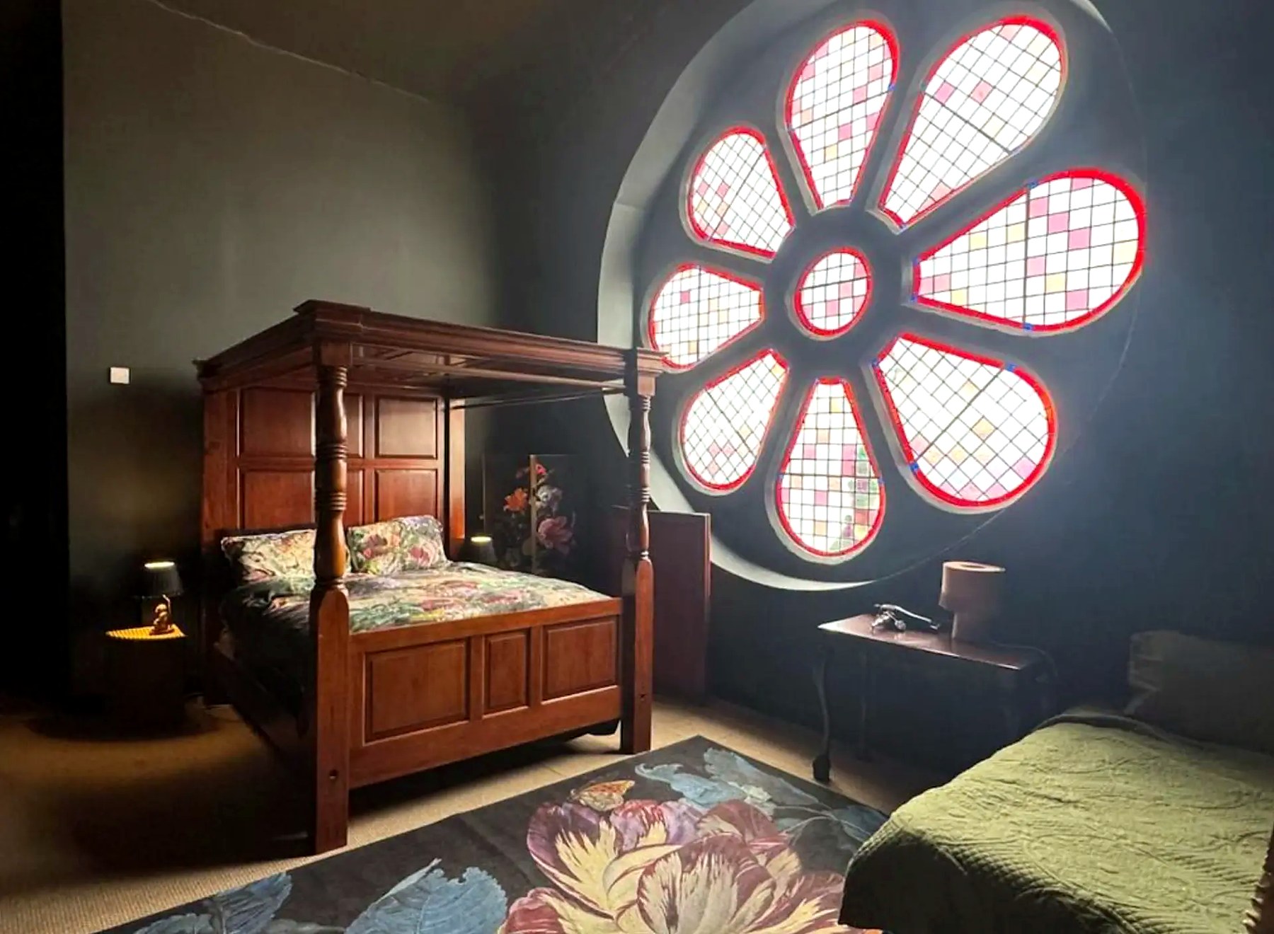Four-poster bed beneath the stained-glass rose window at The Old Church