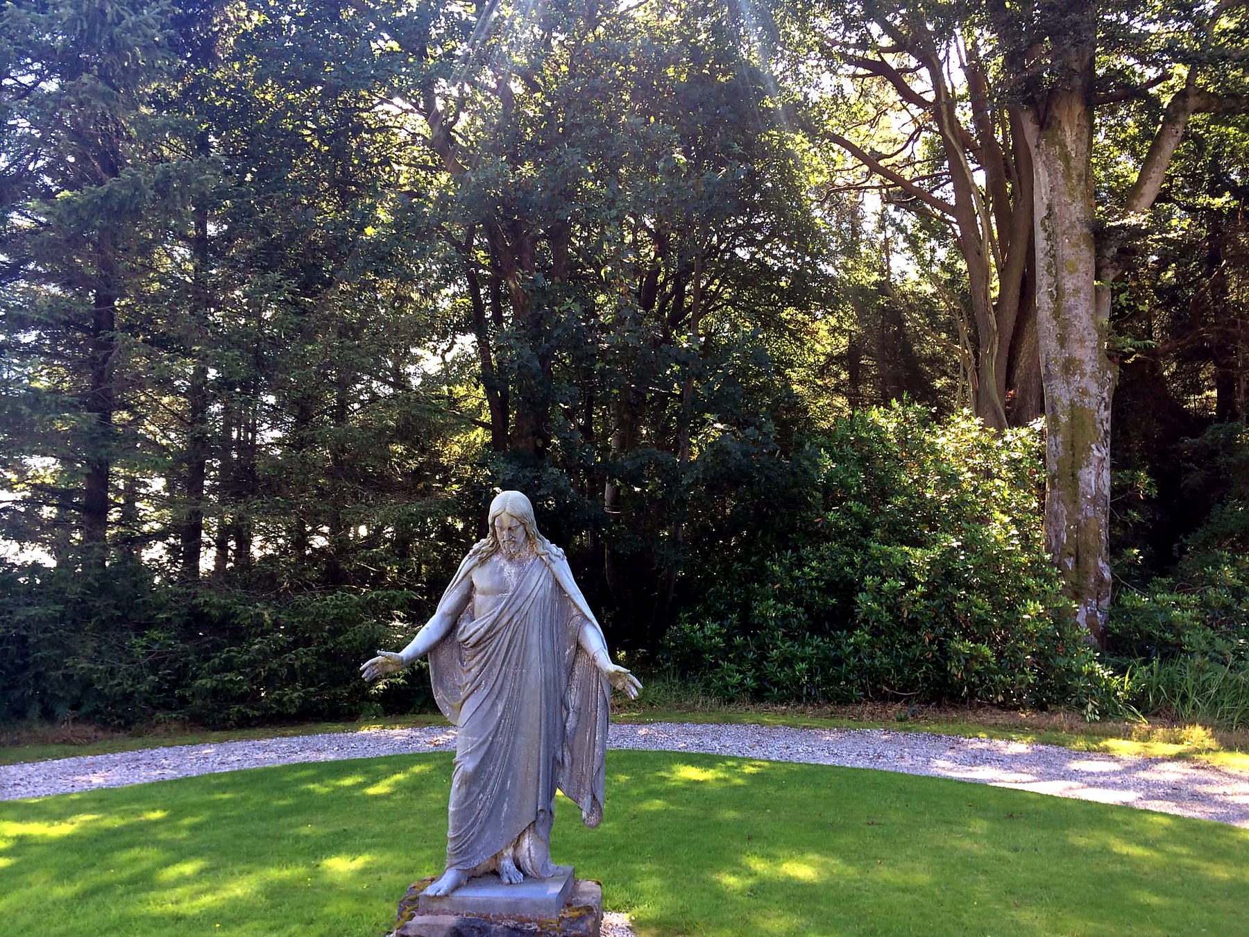 A weathered marble statue on a lawn ringed by tall trees on the Mount Stuart estate, Isle of Bute