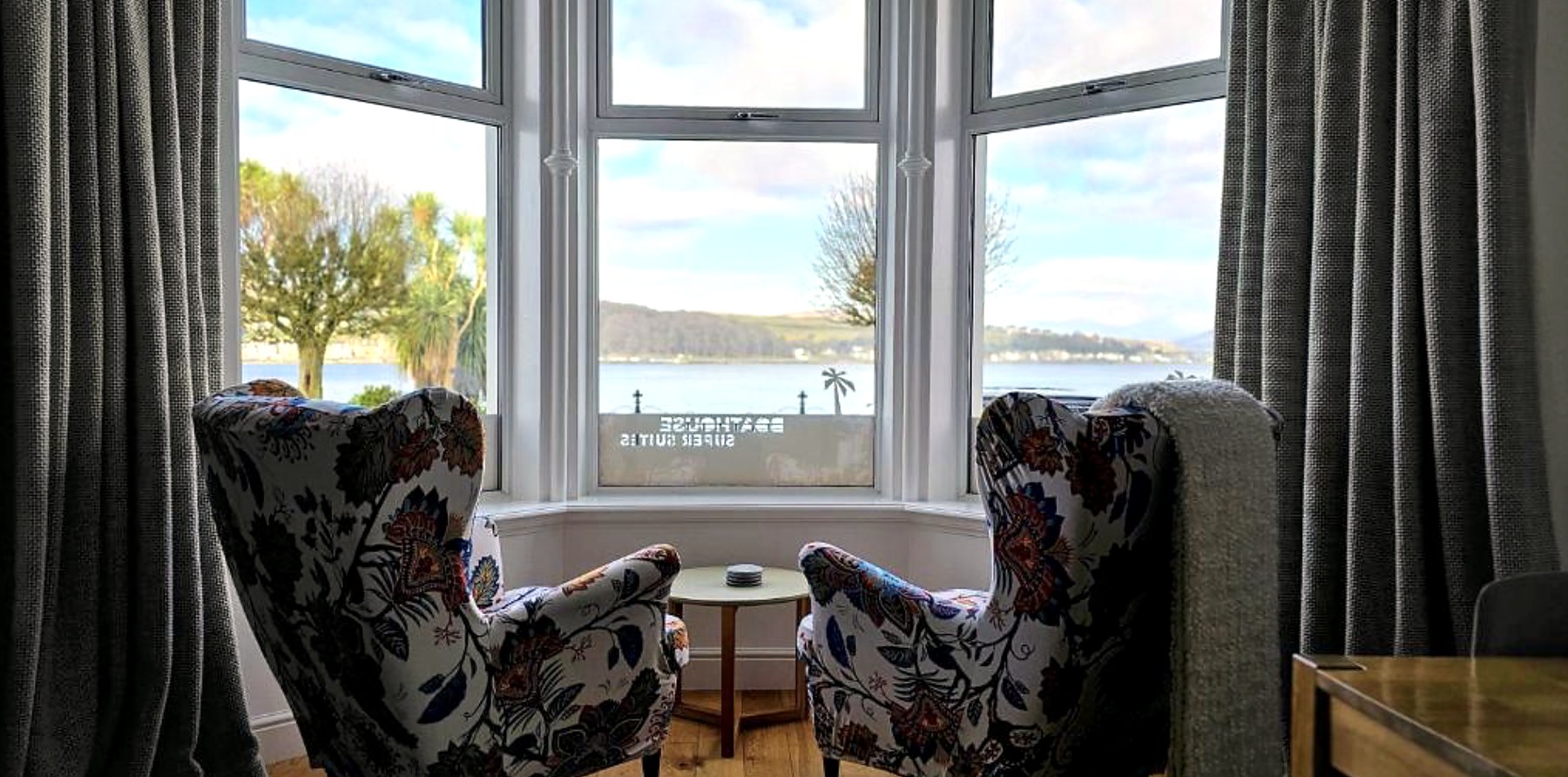 Two patterned armchairs in a bay window at Dairsie Seaview Flat looking across Rothesay Bay