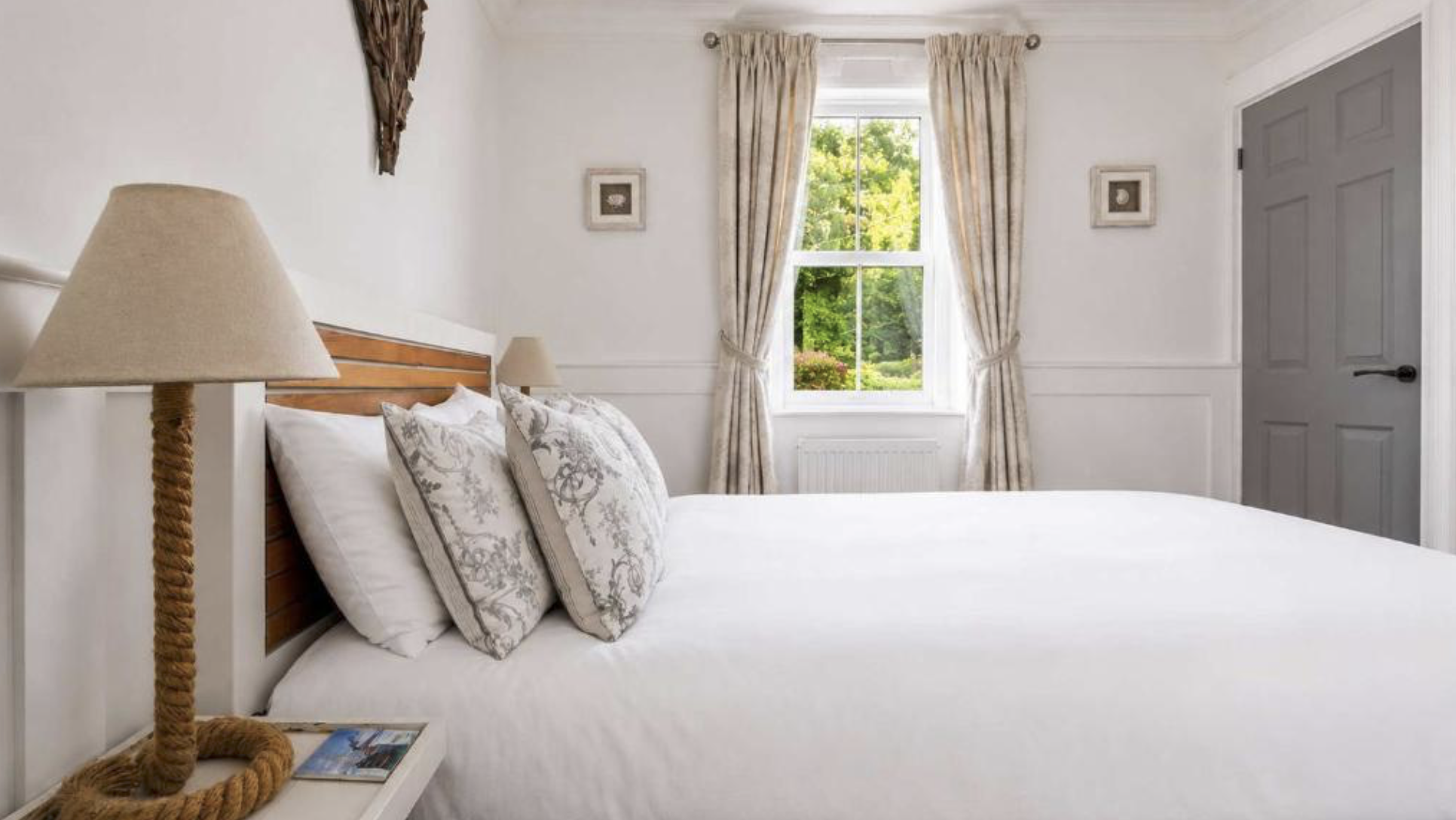A double bedroom at Melbourne Place with white linen, rope lamps and a garden view