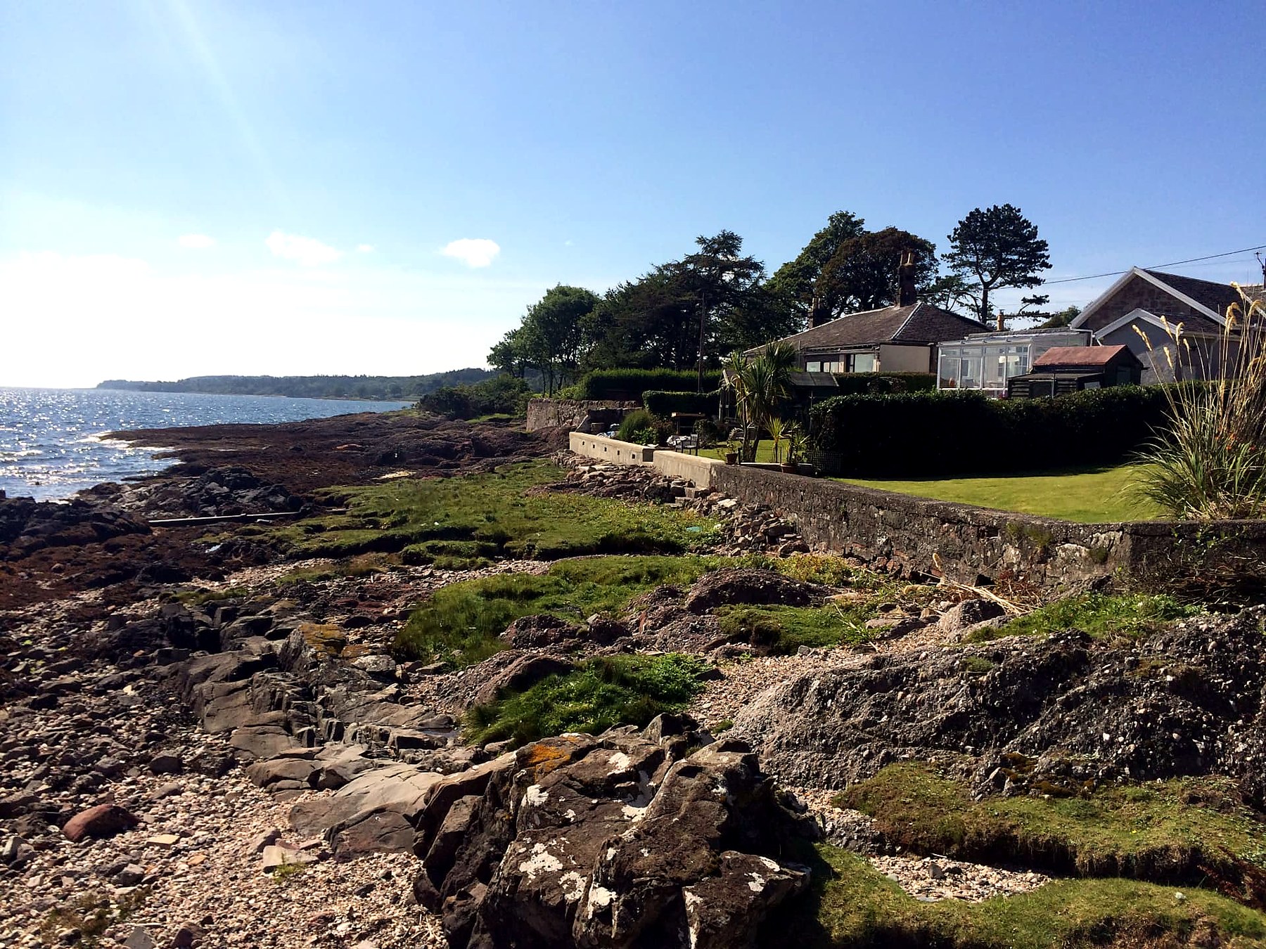 Whitewashed cottage with a conservatory above the rocky shore on the east coast of the Isle of Bute