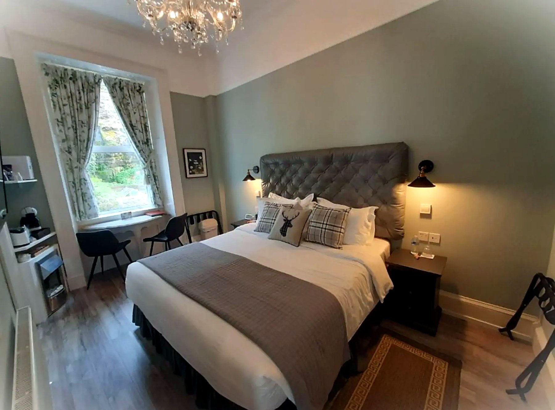 King room at Highlander House with a buttoned headboard, chandelier and garden-facing window