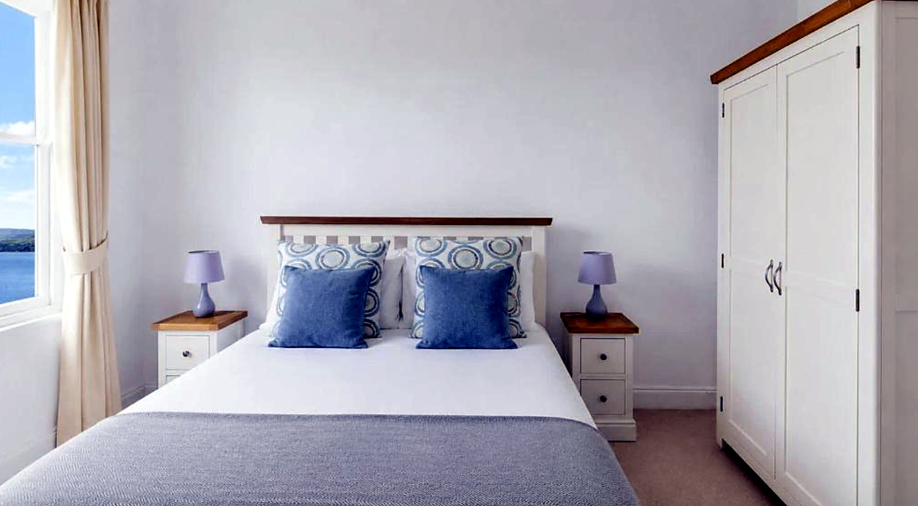Bedroom at Govandale Seaviews with a painted oak bed and a window looking over the water