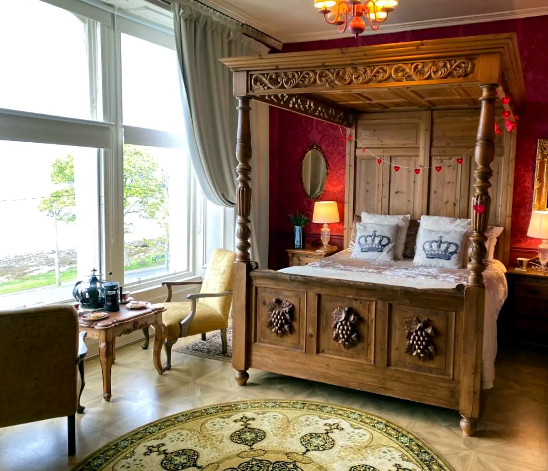 Carved pine four-poster bed in a red-walled bedroom at St Blanes House