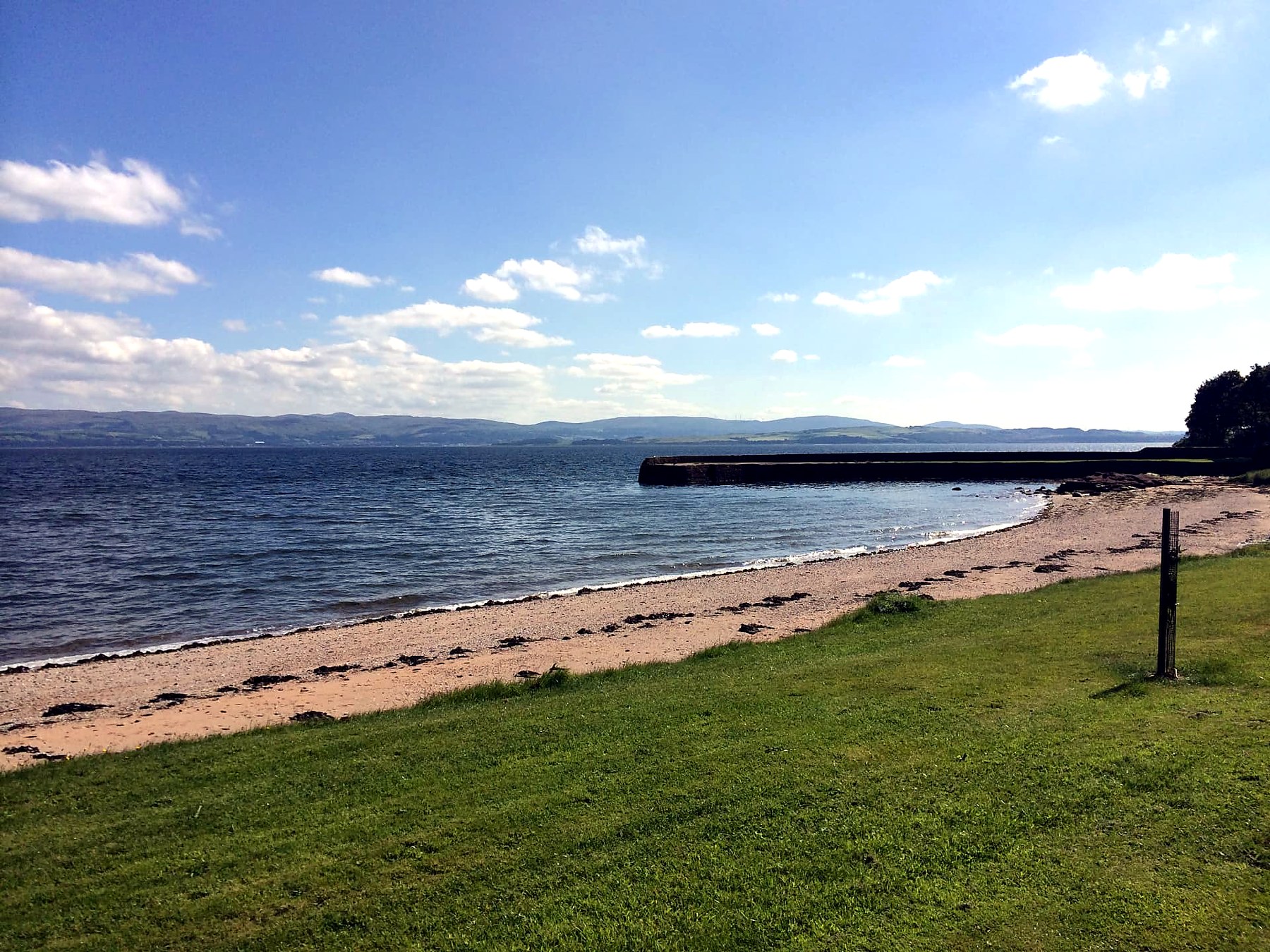 Sandy beach and stone jetty at Kerrycroy looking across the Firth of Clyde from the Isle of Bute