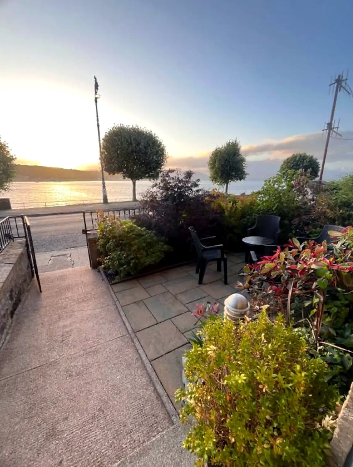 Table and chairs on the terrace at Harbour View as the sun sets over Rothesay Bay