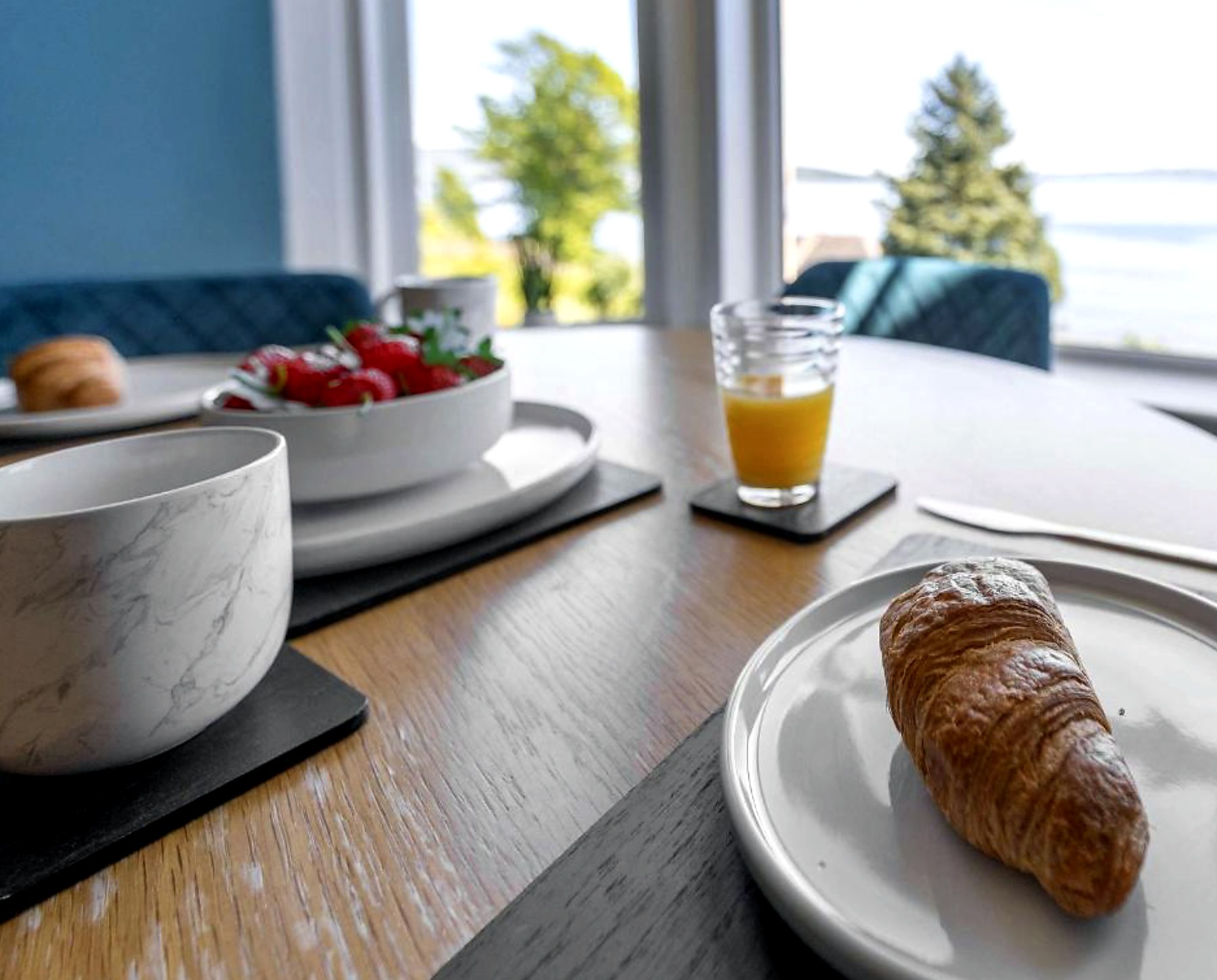 Breakfast of croissants, strawberries and orange juice on a table by the sea-facing window