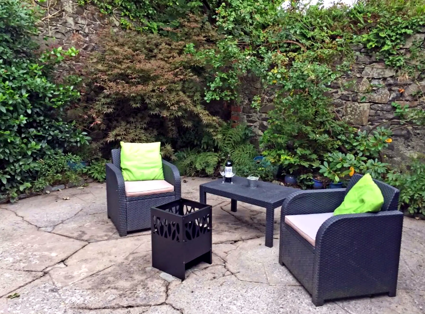 Sheltered walled courtyard at Old Fisherman's Cottage with rattan chairs and fire pit