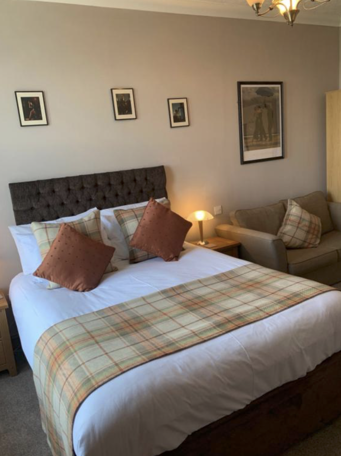 A double bedroom with sofa and tartan accents at Chandlers Apartment